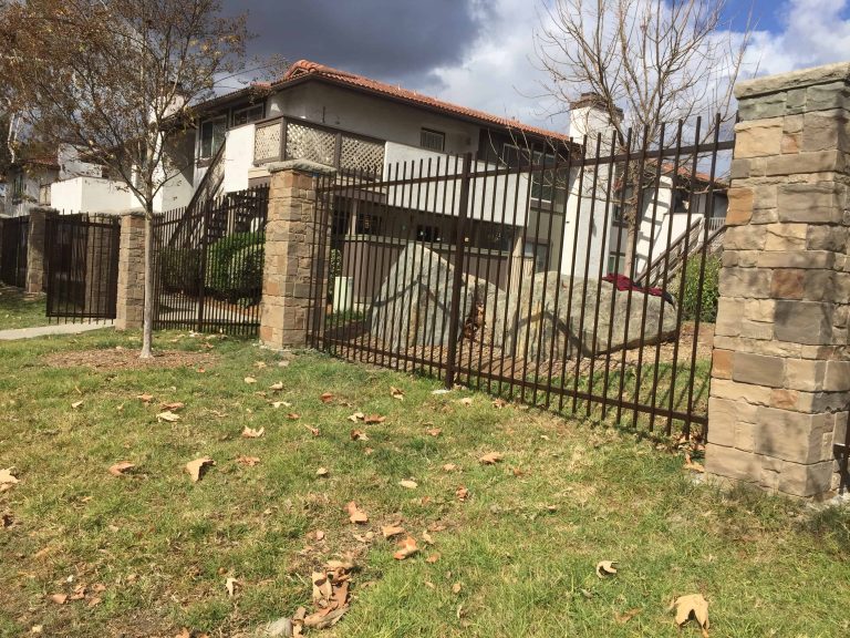 Custom iron fencing between stone pillars at a San Diego property