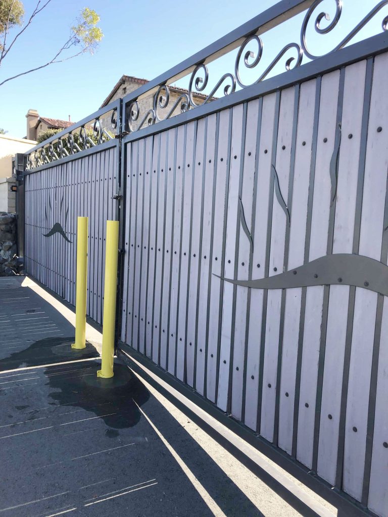 Tall powder coated steel swing gate with ornamental scroll top and solid infill