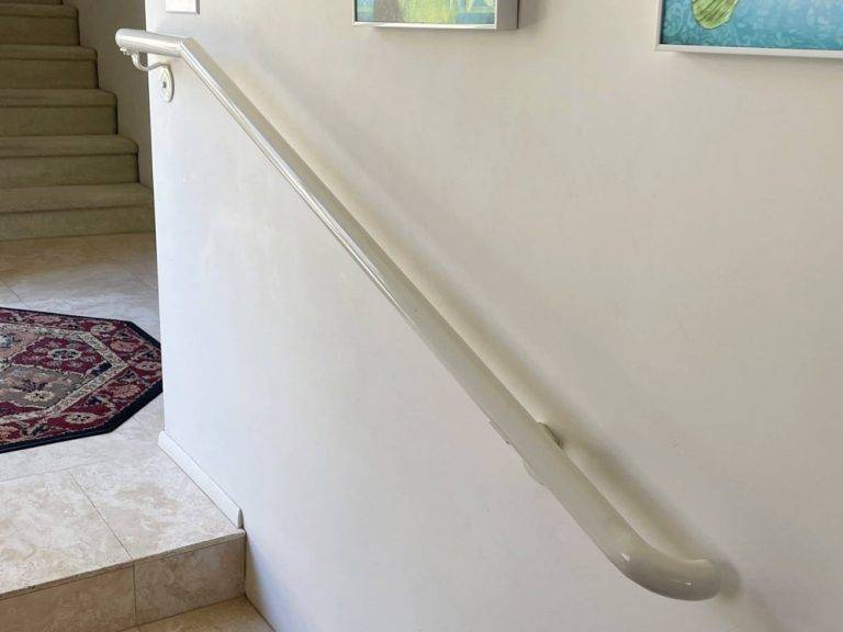 Wall-mounted single hand railing installed along interior stairs