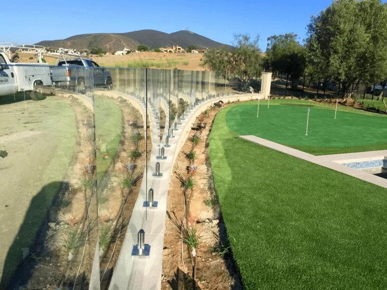 Curved run of tempered glass panels on stainless spigots along a hillside lawn with mountain views