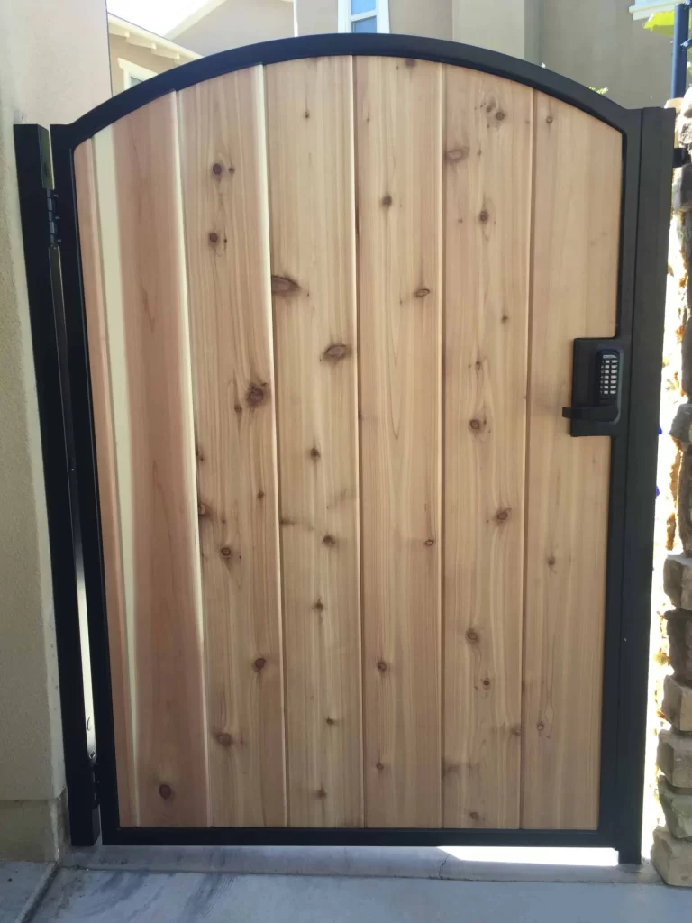 Arched-top cedar walk gate on a black steel frame with an electronic keypad lock