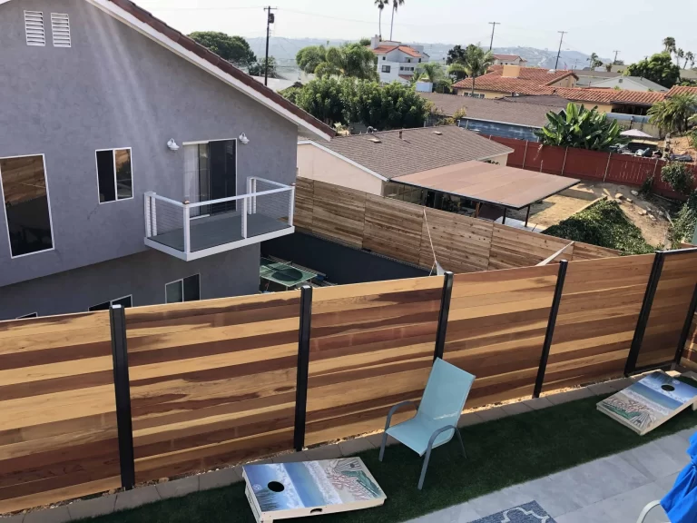 Horizontal redwood board fence on black steel posts around a San Diego backyard with a hillside view