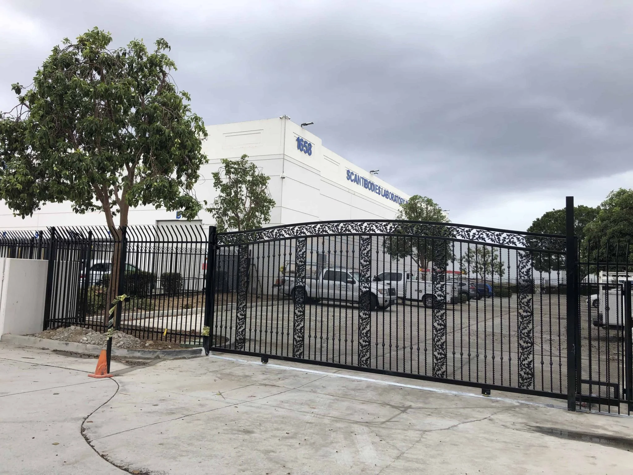 Powder coated ornamental steel sliding gate with scroll panels at a commercial building