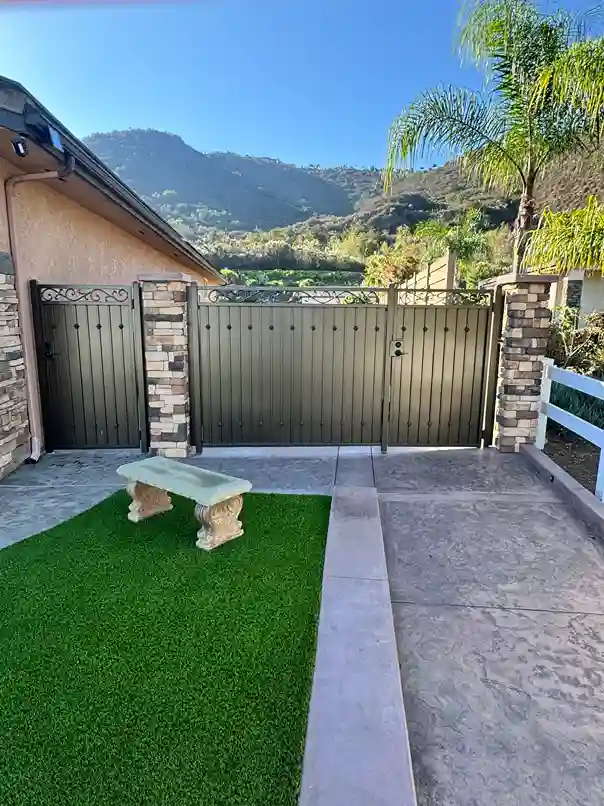 Bronze solid steel gates between stone pillars at a hillside property with mountain views