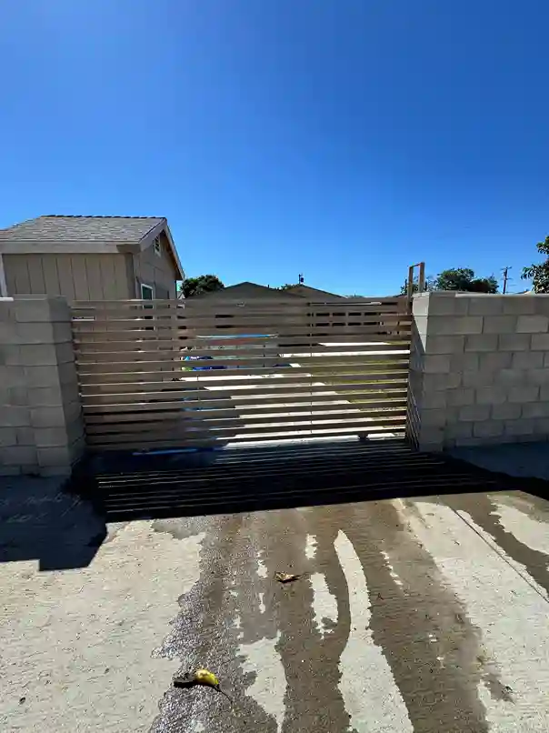 Tan horizontal-slat steel sliding gate between block walls