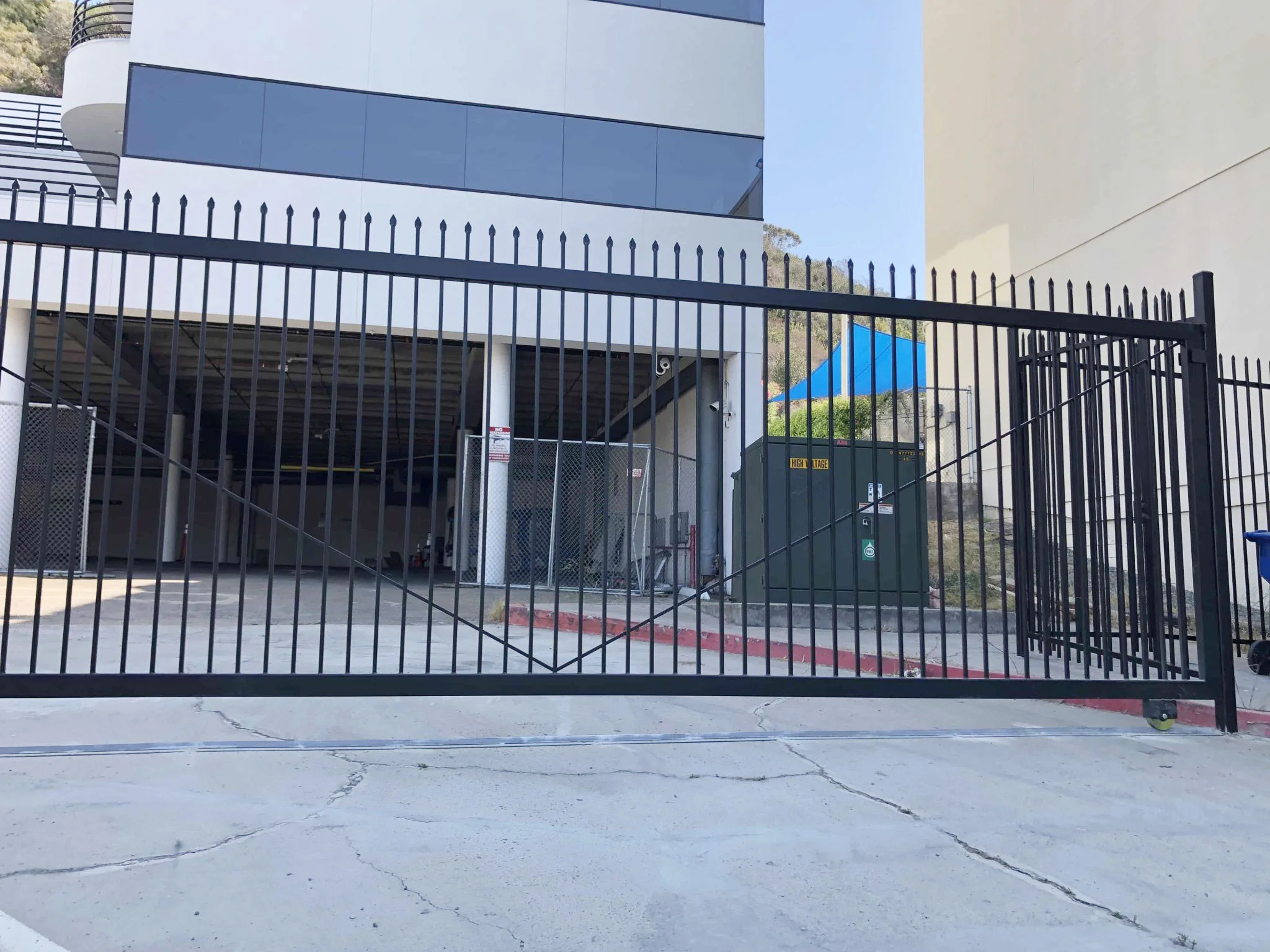 Black steel cantilever slide gate with diagonal bracing at a commercial building garage entrance